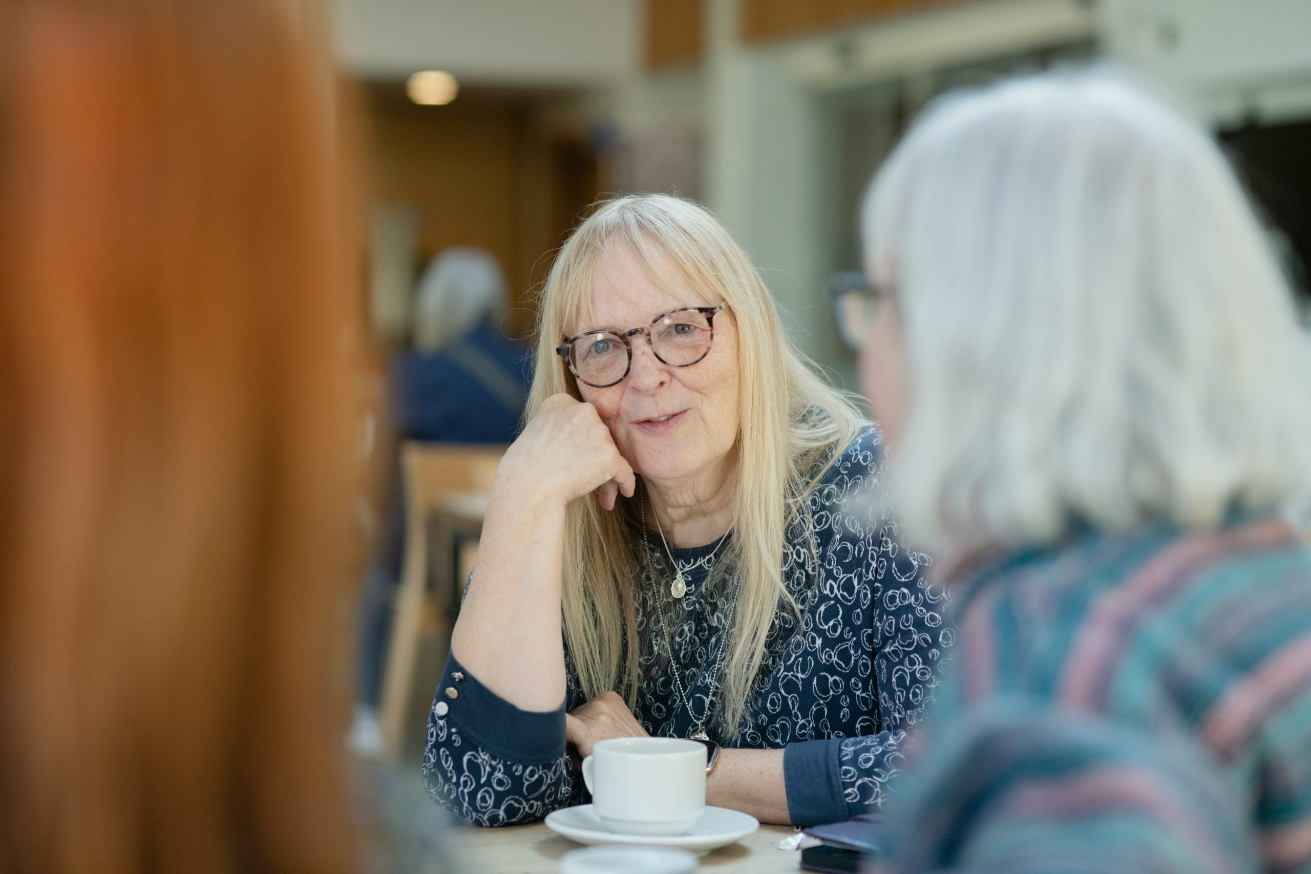 a senior woman smiling with a cup of coffee